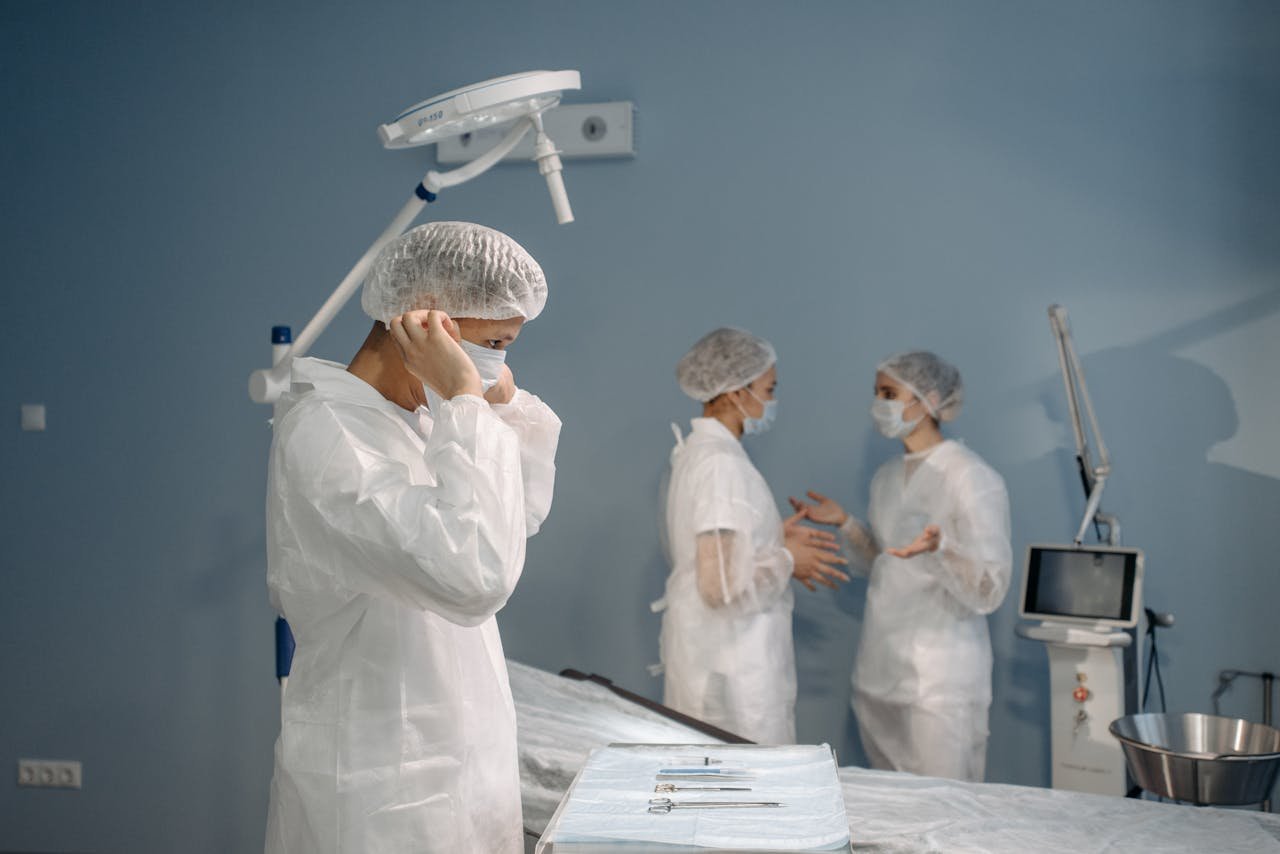 Doctors in PPE preparing for surgery in a clinical setting.